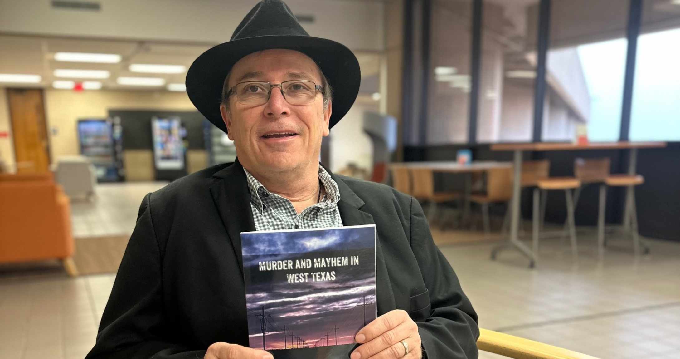 Profesor sosteniendo un libro sonriendo a la cámara