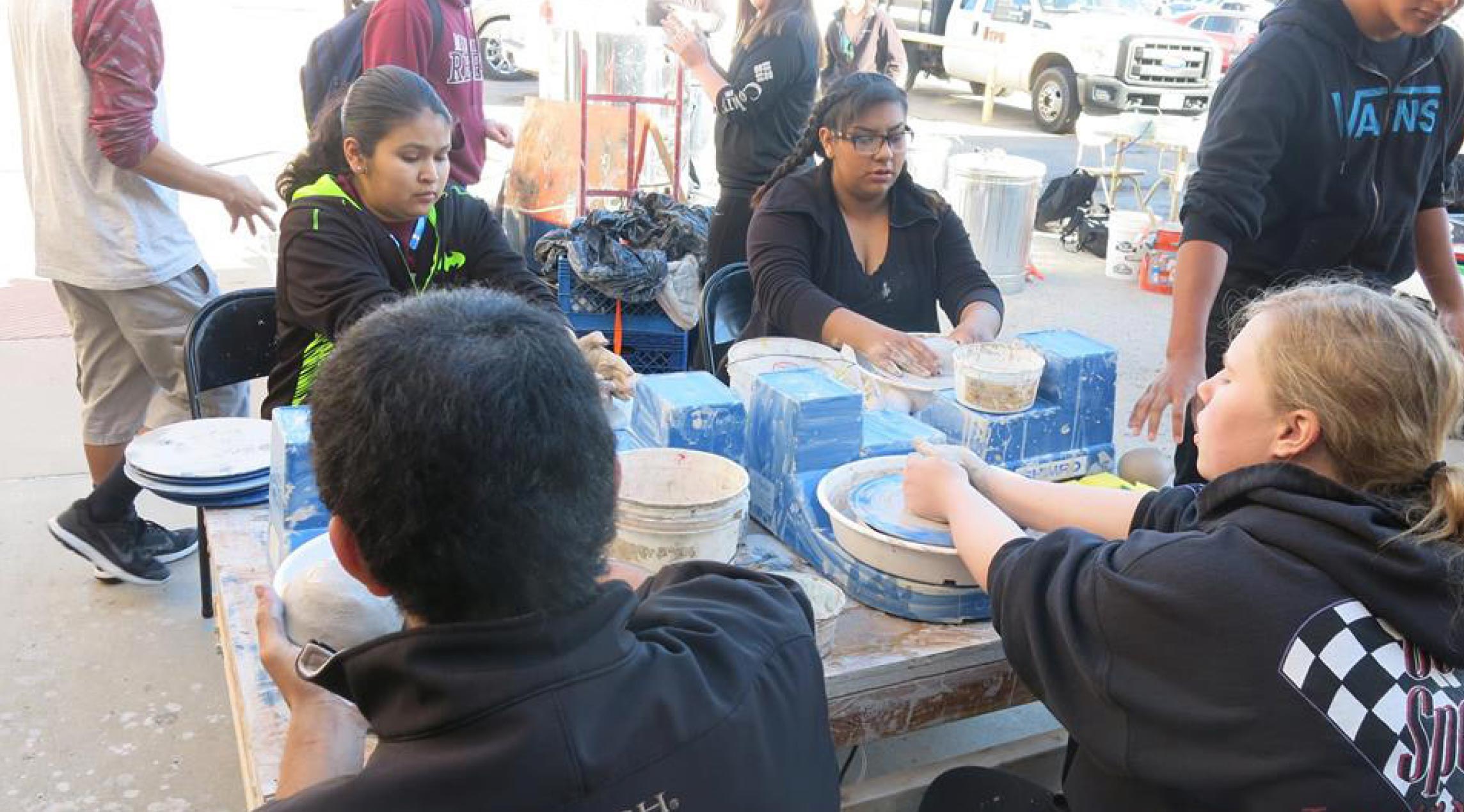 Estudiantes creando vasijas de barro.