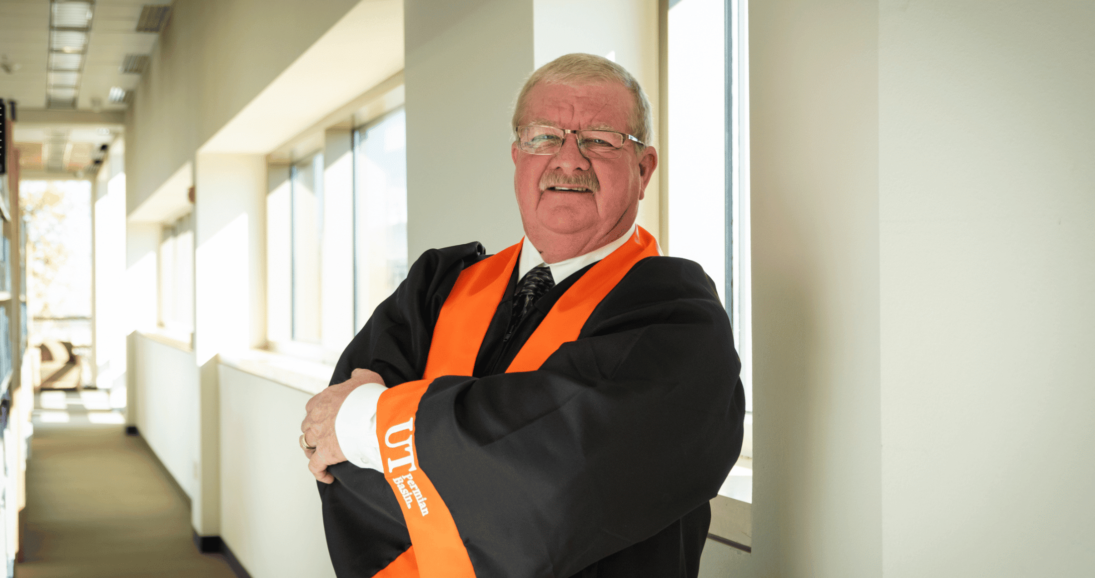 Scott Morton posing with in graduate regalia