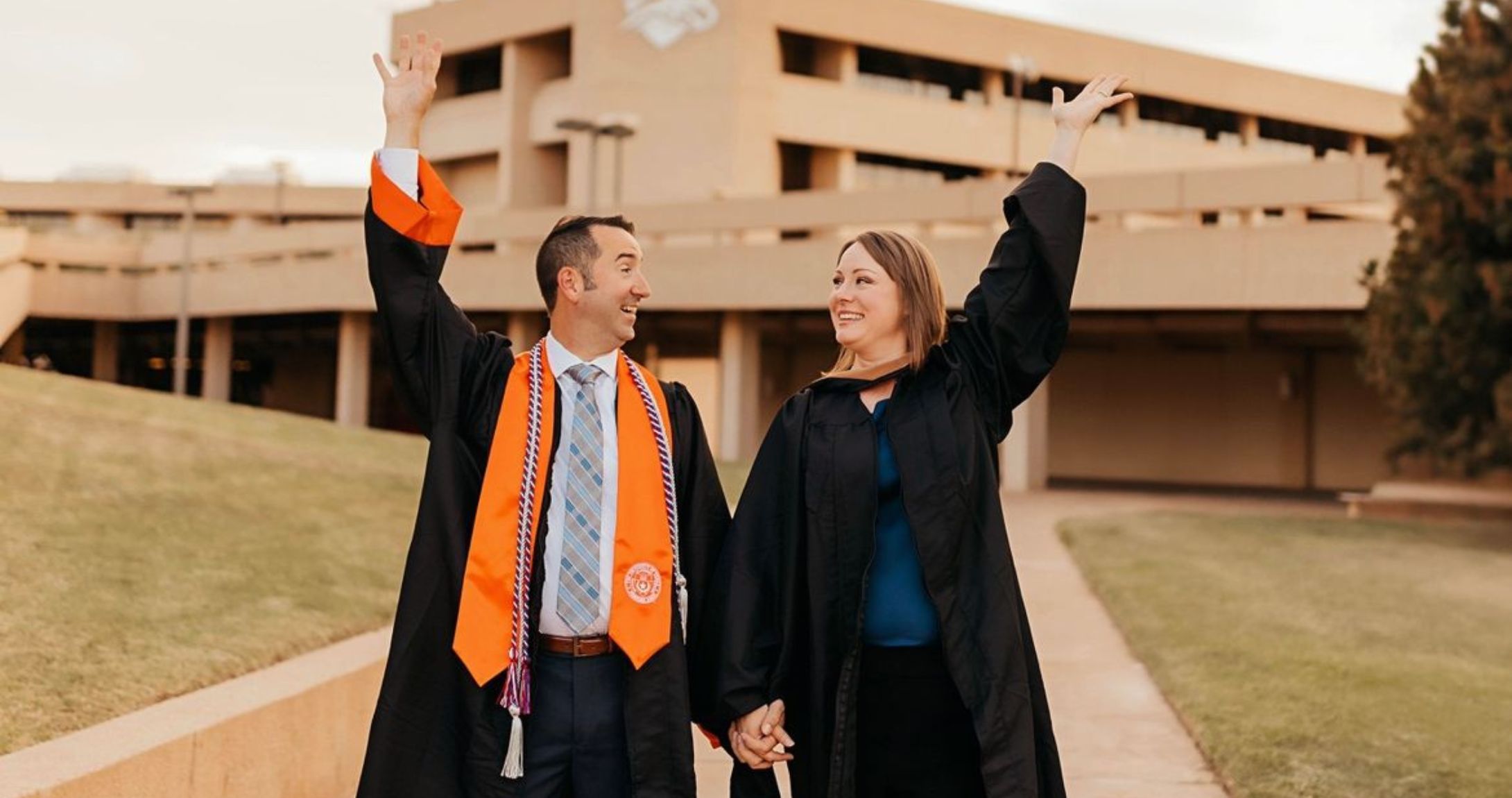 Two grads throwing caps in the air