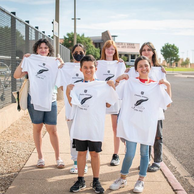 Niños sonriendo sosteniendo camisetas