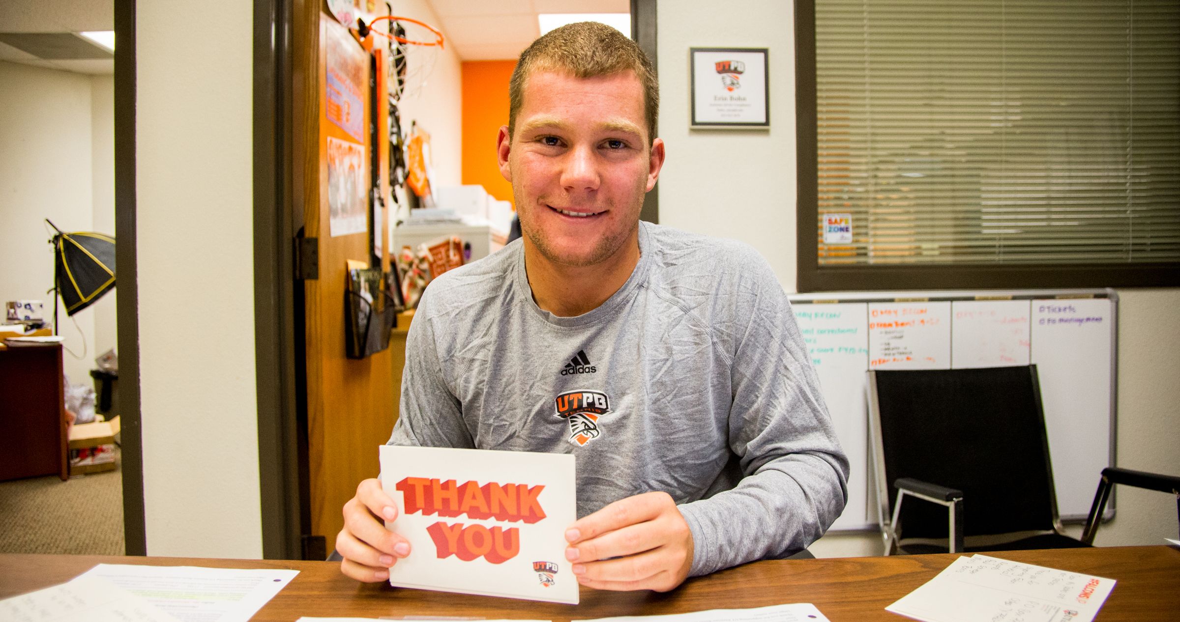 Student-athlete smiling holding thank you card
