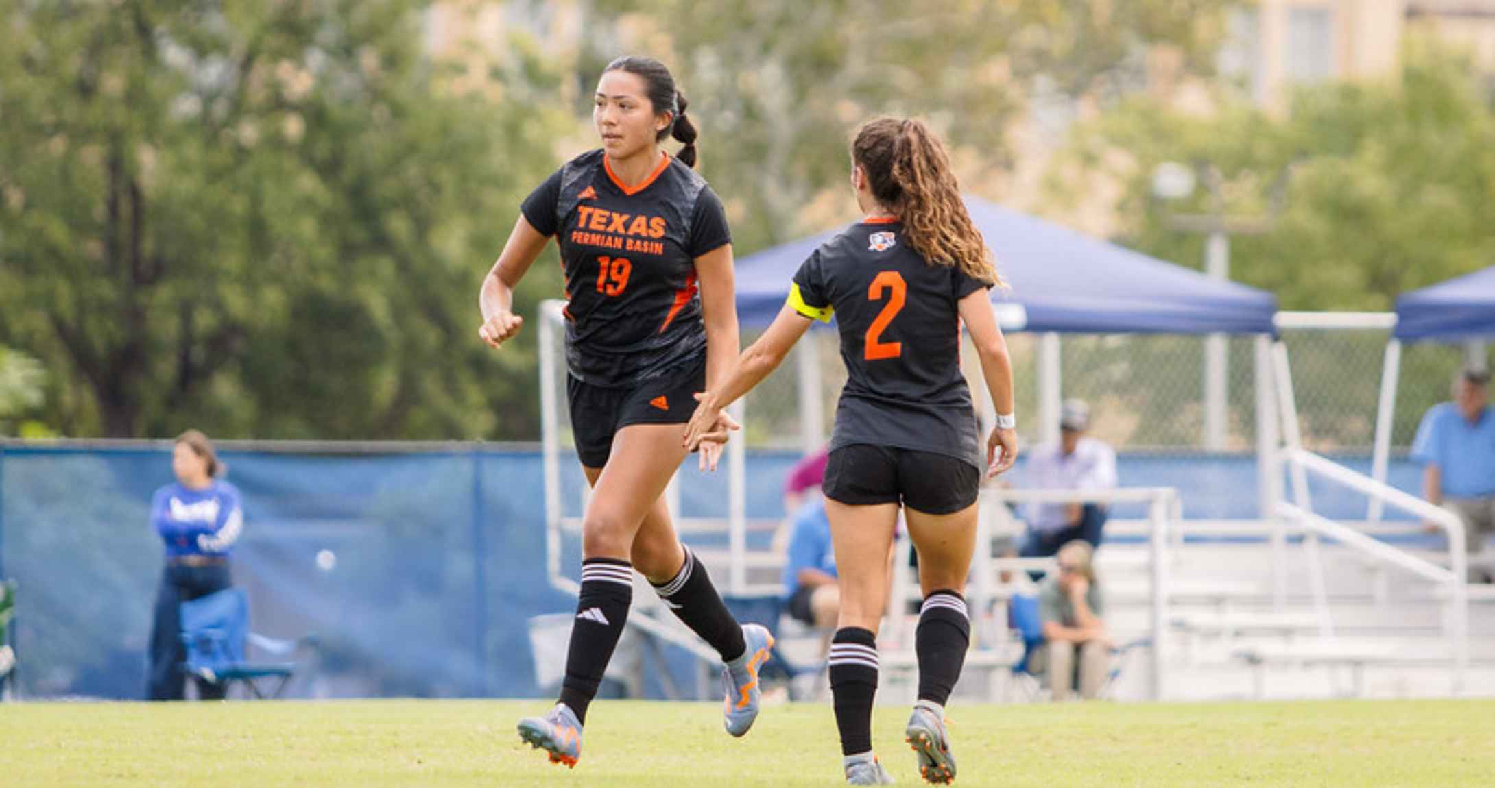 Women's soccer players high-five on field